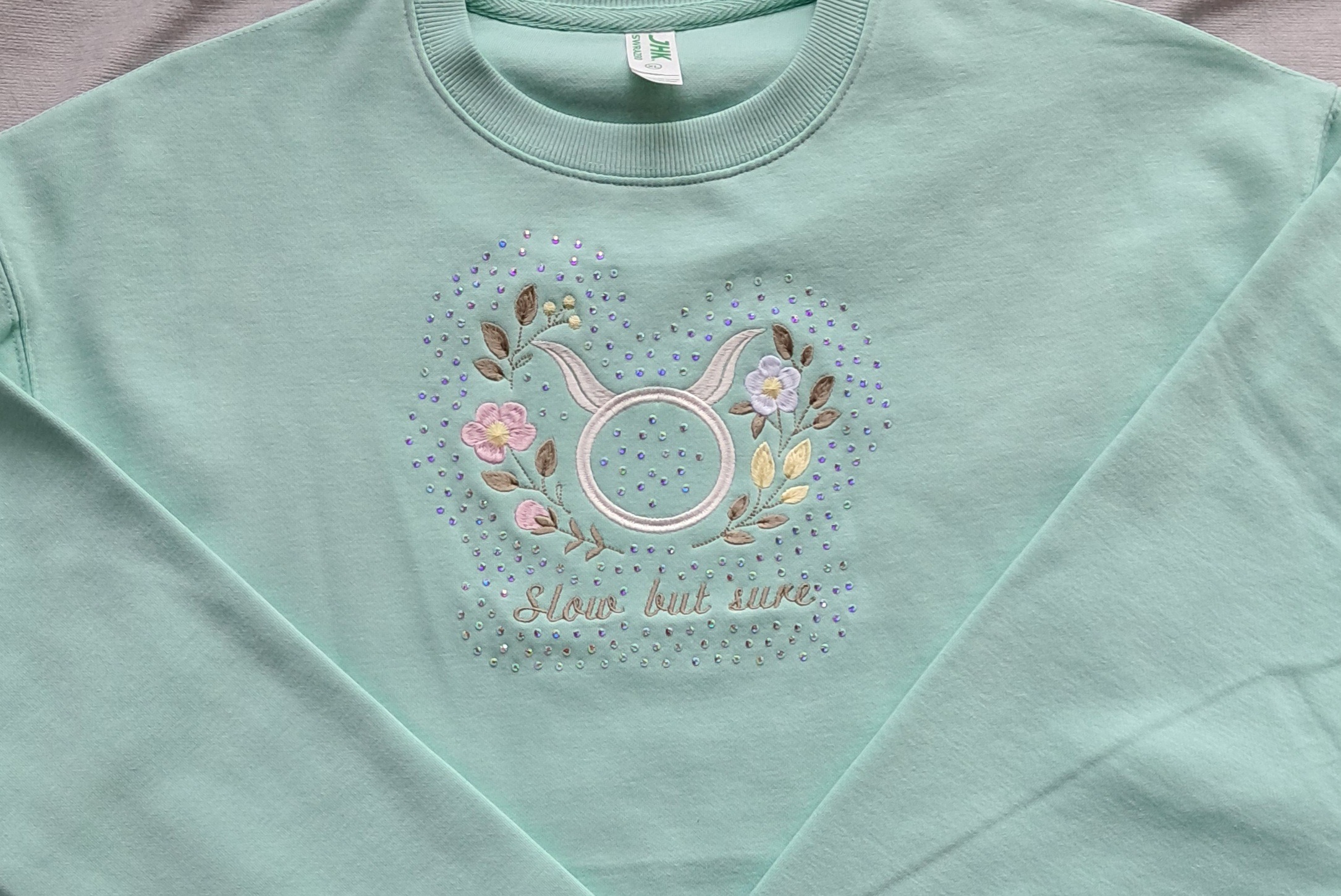 Tähtkuju märgiga ja tikitud lilledega pusa +kristallid